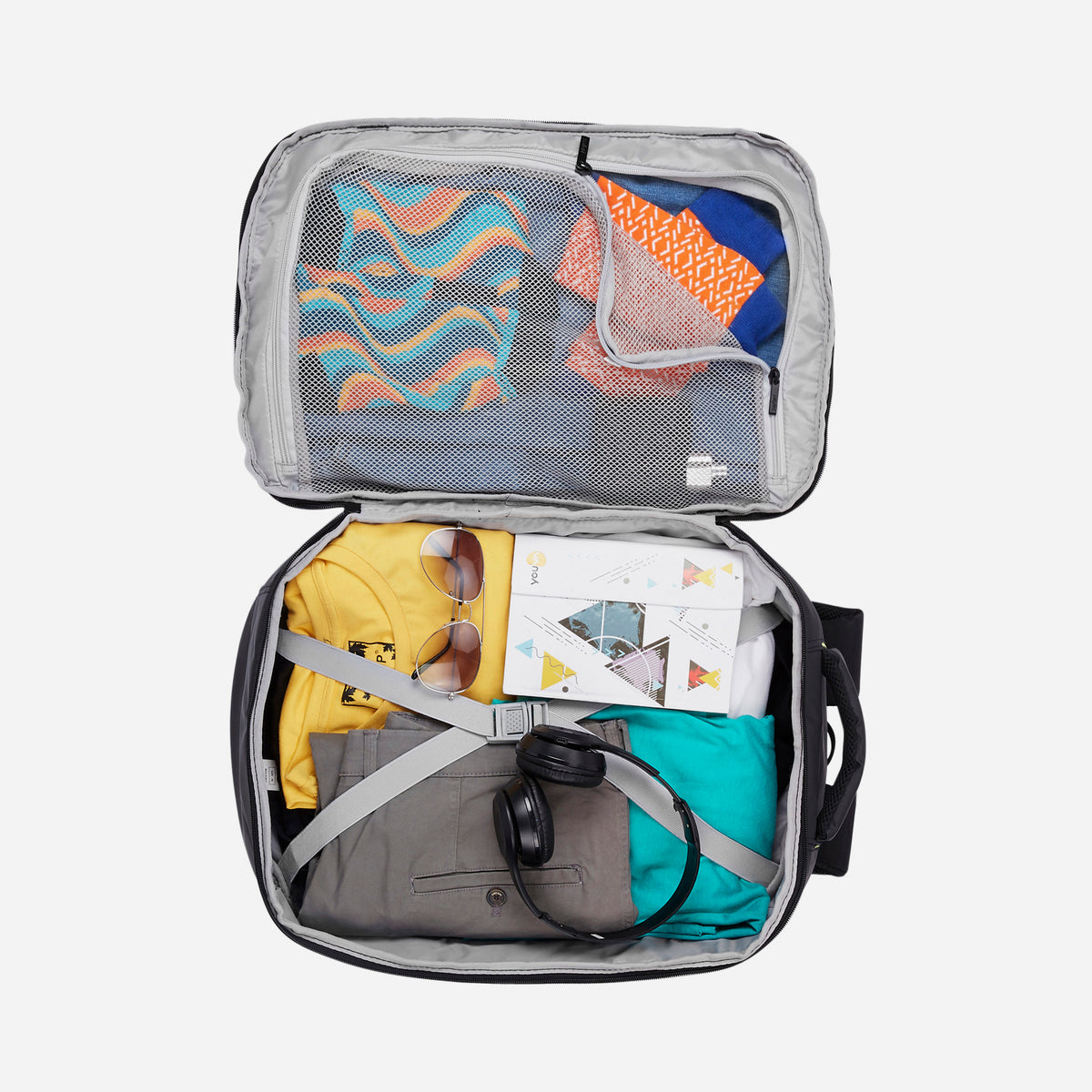 The interior view of an open Safari backpack organized with clothes, headphones, and a map.